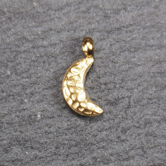 Halbmond-Anhänger, goldfarben und glänzend, reliefartige gehämmerte Textur, organisch geschwungene Mondsichelform mit kleiner Öse oben.