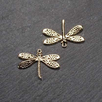Libellen-Anhänger (Vorder- und Rückseite) aus goldfarbenem, glänzendem Metall mit durchbrochenen, netzartigen Flügeln, schlankem segmentiertem Körper und kleiner runder Aufhängöse.