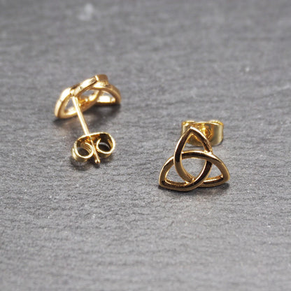 Paar goldfarbener Ohrstecker mit offen gearbeitetem Triquetra-Knoten, glänzende Oberfläche und sichtbaren Schmetterlingsverschlüssen.