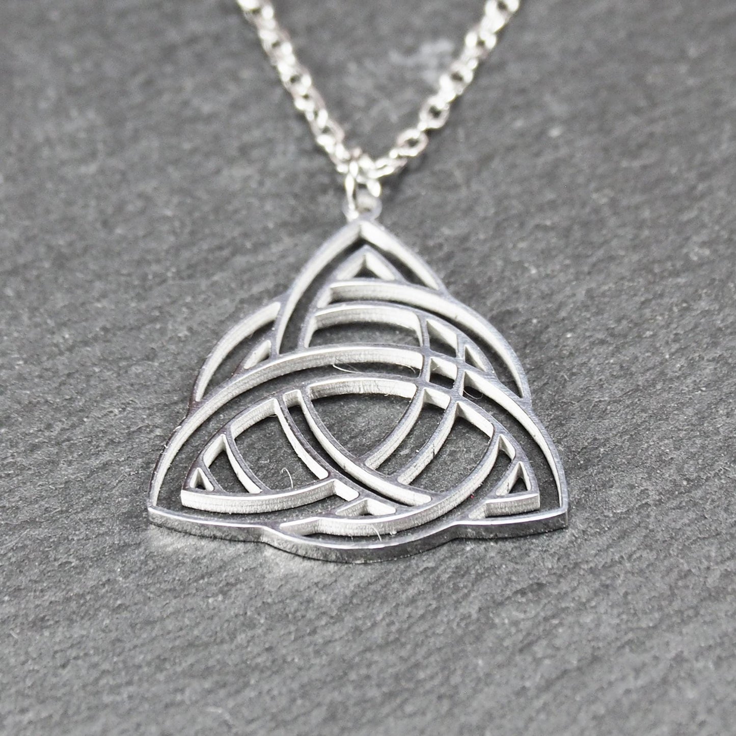 Anhänger, silberfarben glänzend; dreieckige, offene Triquetra-Knotenform mit filigraner Durchbruchstruktur und sichtbarer Öse an feiner Gliederkette.