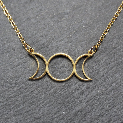 Collier mit goldfarbenem, offenem Anhänger in dreifacher Mondform (Mondsichel-Kreis-Mondsichel), an einer feinen Gliederkette mittels Ösen befestigt.
