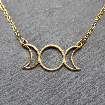 Collier mit goldfarbenem, offenem Anhänger in dreifacher Mondform (Mondsichel-Kreis-Mondsichel), an einer feinen Gliederkette mittels Ösen befestigt.