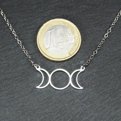 Silberfarbenes Collier mit offenem, filigranem Drei‑Mond‑Anhänger (zwei Mondsicheln und Kreis); 1‑Euro‑Münze als Größenvergleich.