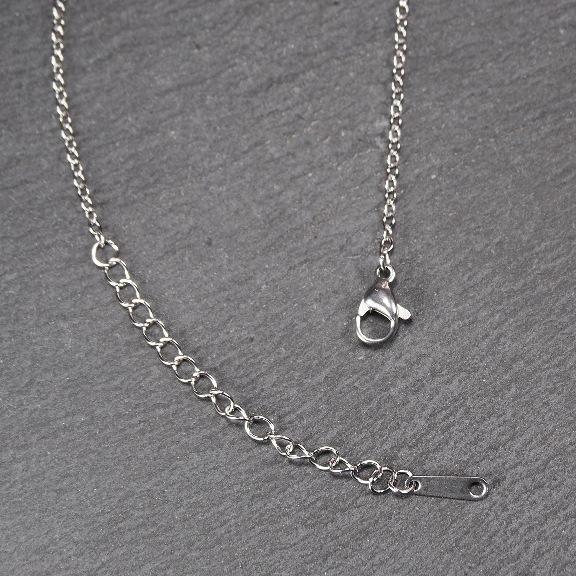 Versilberte Halskette mit feiner Gliederkette, Verlängerungskette mit ovalen Gliedern, Karabinerverschluss und flachem Endplättchen mit Loch.