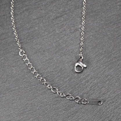 Versilberte Halskette mit feiner Gliederkette, Verlängerungskette mit ovalen Gliedern, Karabinerverschluss und flachem Endplättchen mit Loch.