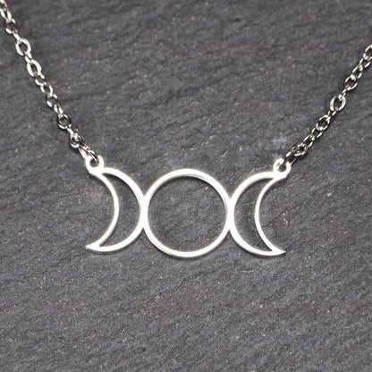 Filigranes silberfarbenes Collier mit offenem, symmetrischem Anhänger in Form dreier Mondphasen (zwei Mondsicheln neben Kreis) an Kette.
