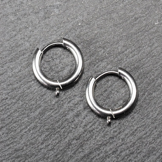 Paar runde silberfarbene Creolen mit hochglänzender, glatter Oberfläche, klappbarem Scharnierverschluss und kleiner geschlossener Öse unten.