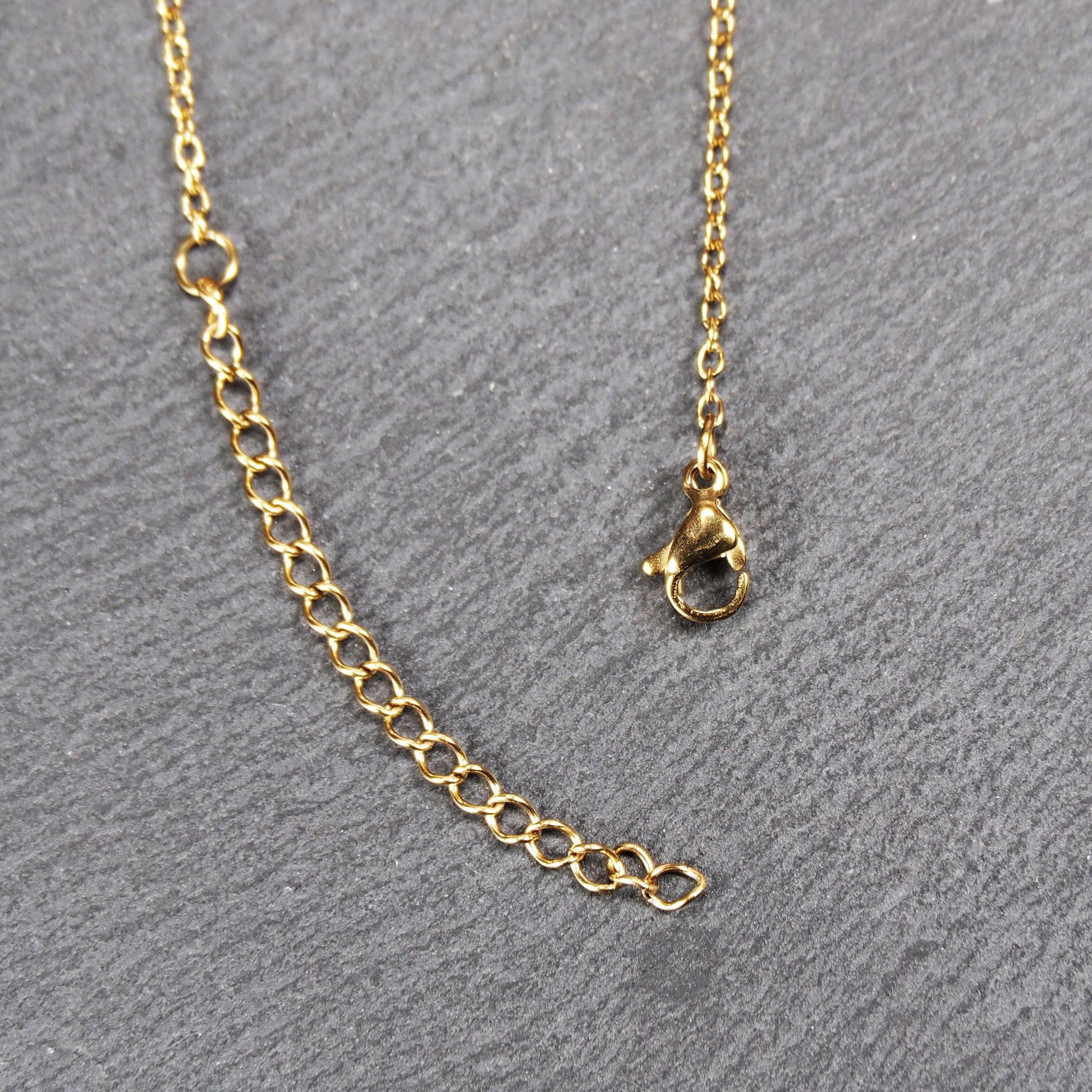 Vergoldeter Anhänger in offener Triquetra-Knotenform mit filigranen Durchbrüchen, an dünner goldfarbener Kette und sichtbarer Öse.