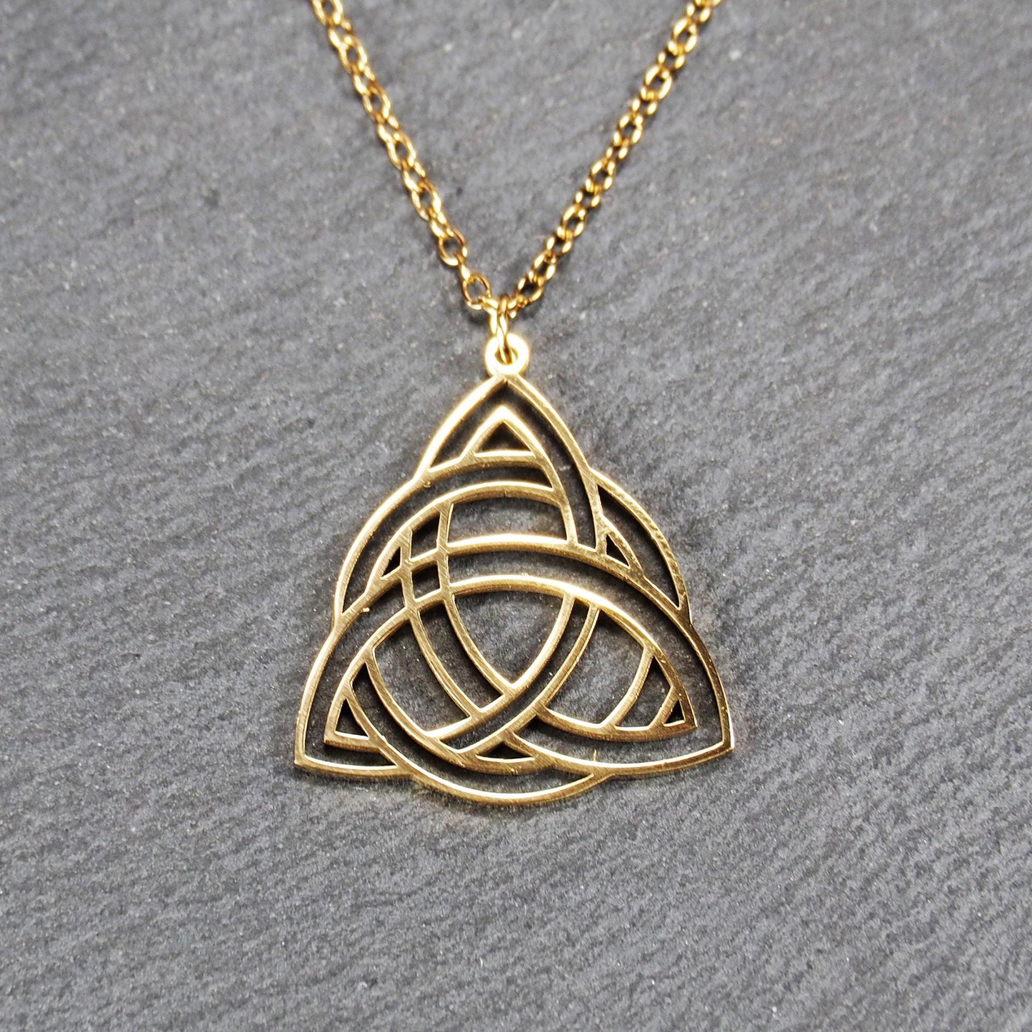 Vergoldeter Anhänger in offener Triquetra-Knotenform mit filigranen Durchbrüchen, an dünner goldfarbener Kette und sichtbarer Öse.