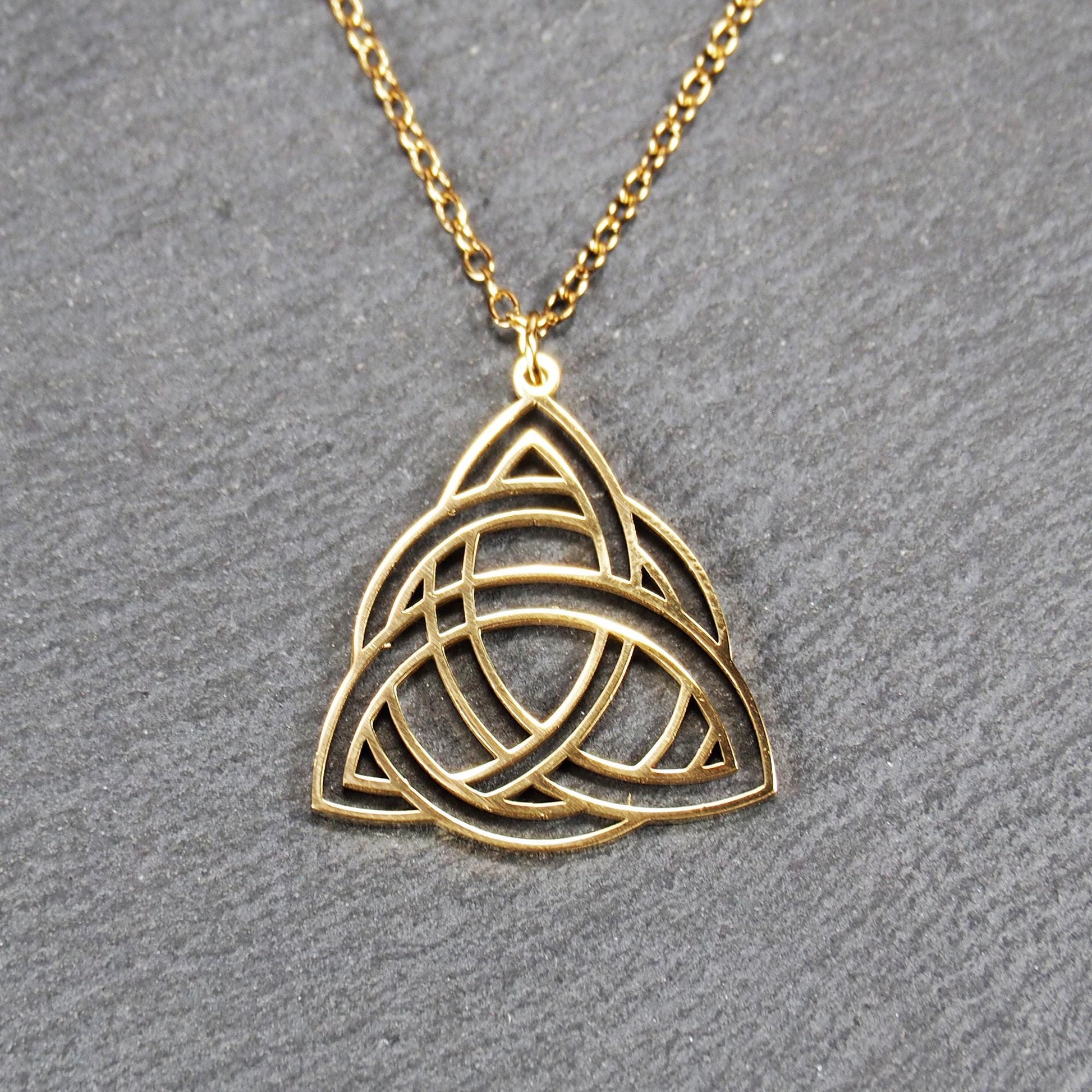 Vergoldeter Anhänger in offener Triquetra-Knotenform mit filigranen Durchbrüchen, an dünner goldfarbener Kette und sichtbarer Öse.