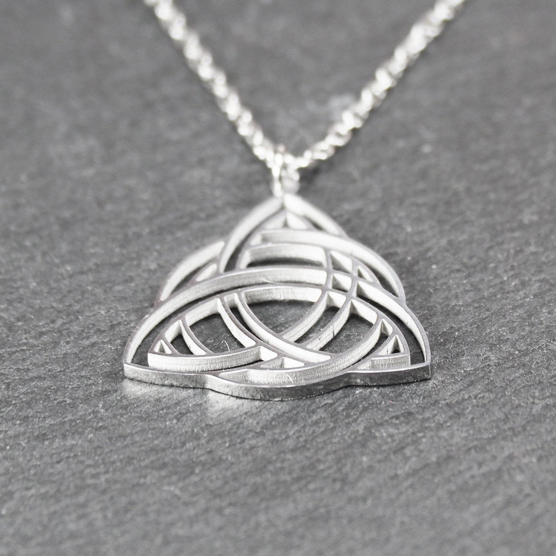 Anhänger, silberfarben glänzend; dreieckige, offene Triquetra-Knotenform mit filigraner Durchbruchstruktur und sichtbarer Öse an feiner Gliederkette.