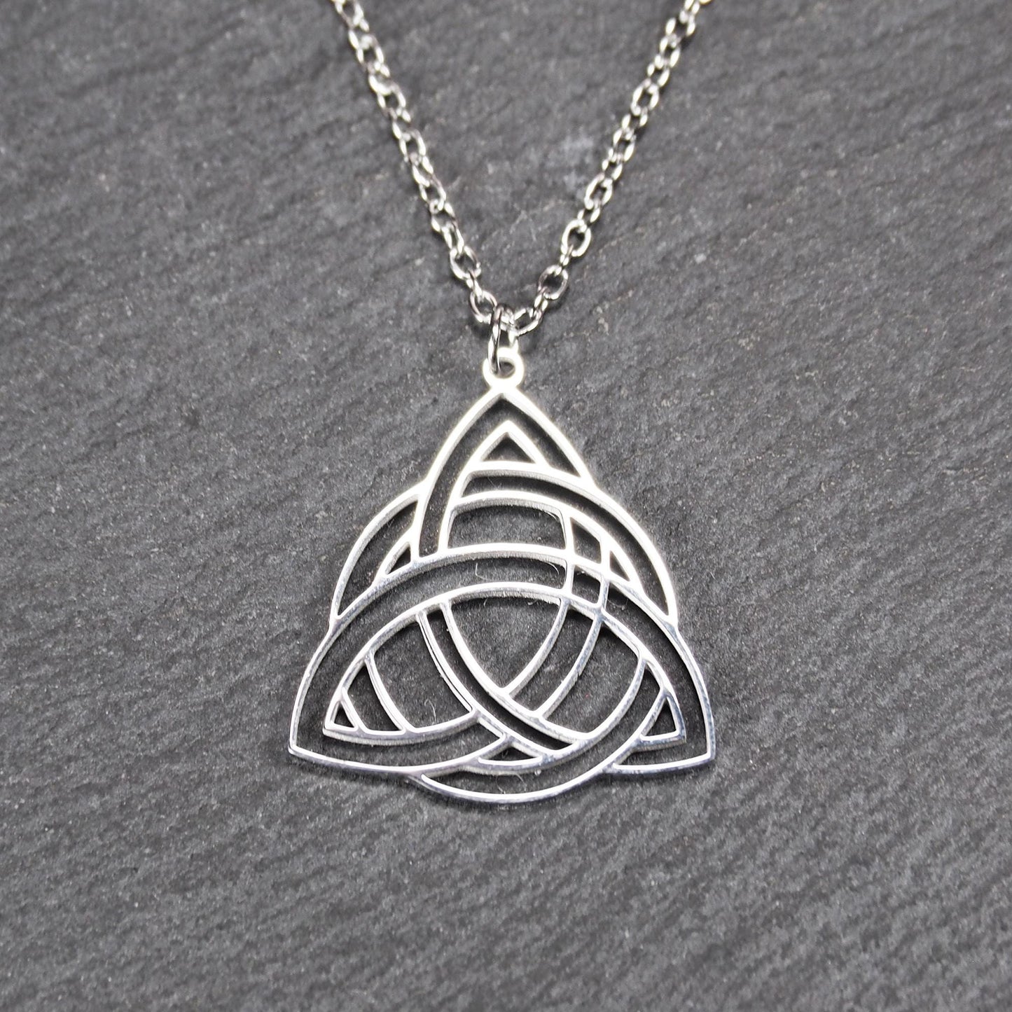 Anhänger, silberfarben glänzend; dreieckige, offene Triquetra-Knotenform mit filigraner Durchbruchstruktur und sichtbarer Öse an feiner Gliederkette.