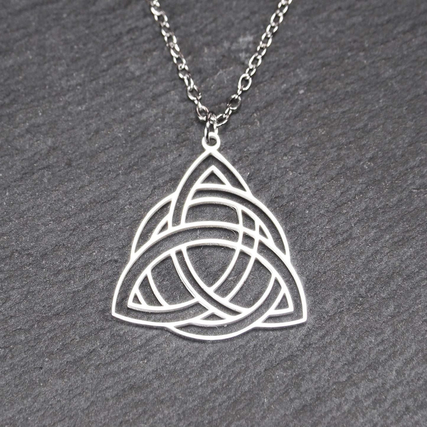 Anhänger, silberfarben glänzend; dreieckige, offene Triquetra-Knotenform mit filigraner Durchbruchstruktur und sichtbarer Öse an feiner Gliederkette.